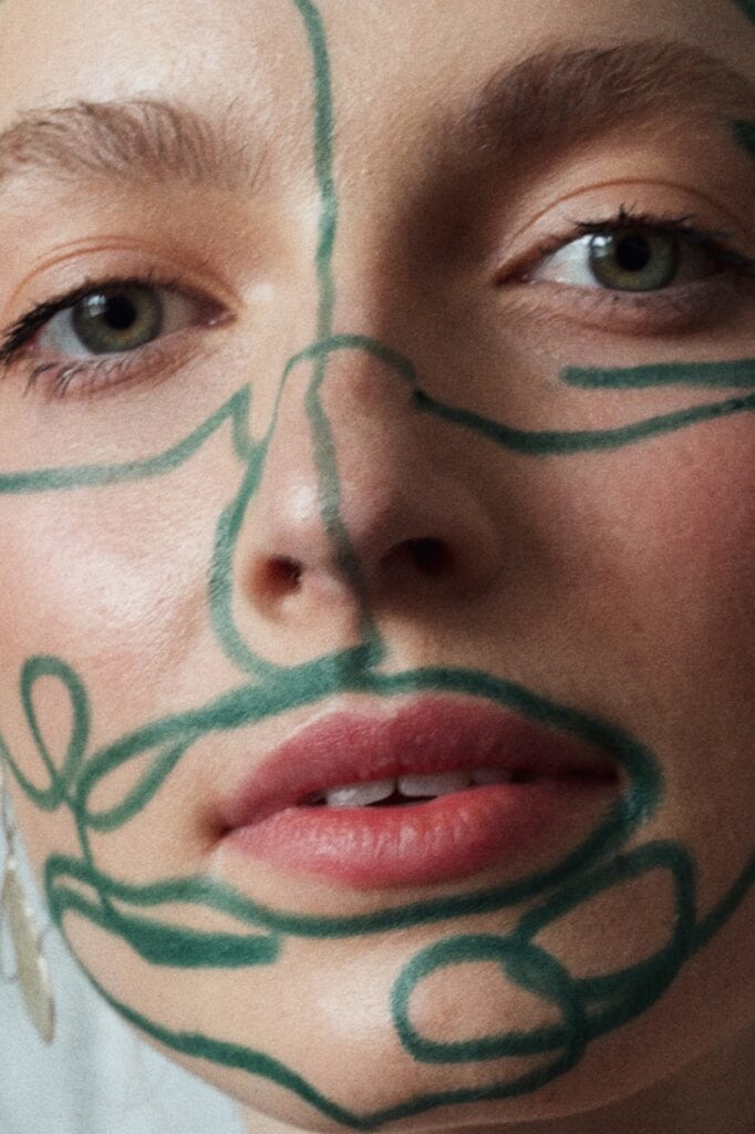 Close up of a model's face with with organic green lines drawn over the face